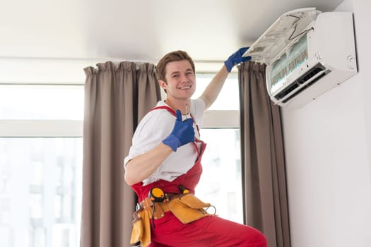 Professional technician maintaining modern air conditioner indoors