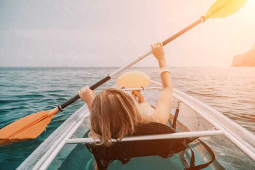 Woman in kayak back view. Happy young woman with long hair floating in transparent kayak on the crystal clear sea. Summer holiday vacation and cheerful female people having fun on the boat.