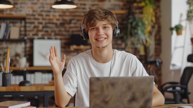 A young man with headphones sitting at a laptop computer