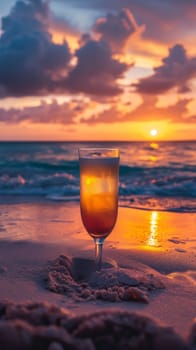A glass of a drink sitting on the beach at sunset