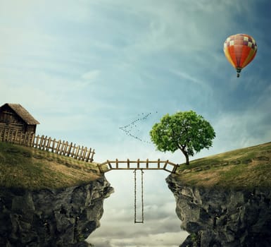 Country image with a wood bridge connecting two hills. Idyllic view of a old cabin with fence and a tree near the cliff and a swing in the middle