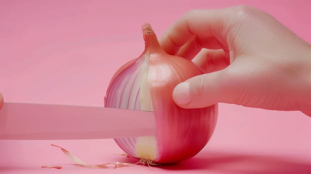 A person cutting an onion with a knife on pink background