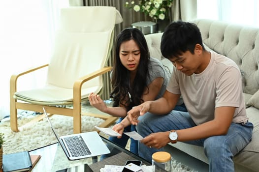 Serious young married couple checking their domestic bills and calculating family budget at home.