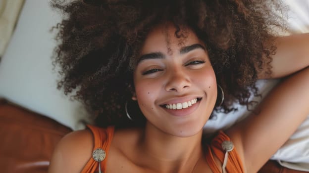 A woman with large afro smiling while laying on a bed