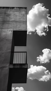 A black and white photo of a balcony with clouds in the background