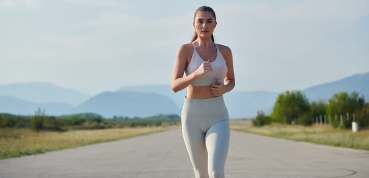 An athletic woman finds freedom and joy in a healthy lifestyle, running through a beautiful road trail at sunrise.