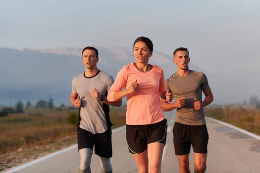 A group of friends, athletes, and joggers embrace the early morning hours as they run through the misty dawn, energized by the rising sun and surrounded by the tranquil beauty of nature.