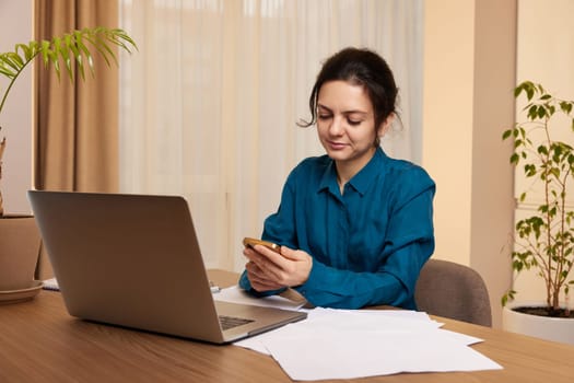 beautiful businesswoman working on laptop and communicates with customer by phone at home