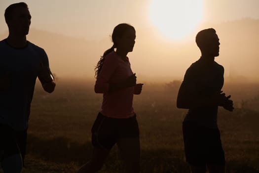 A group of friends, athletes, and joggers embrace the early morning hours as they run through the misty dawn, energized by the rising sun and surrounded by the tranquil beauty of nature.