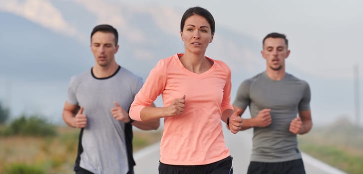 A group of friends, athletes, and joggers embrace the early morning hours as they run through the misty dawn, energized by the rising sun and surrounded by the tranquil beauty of nature.