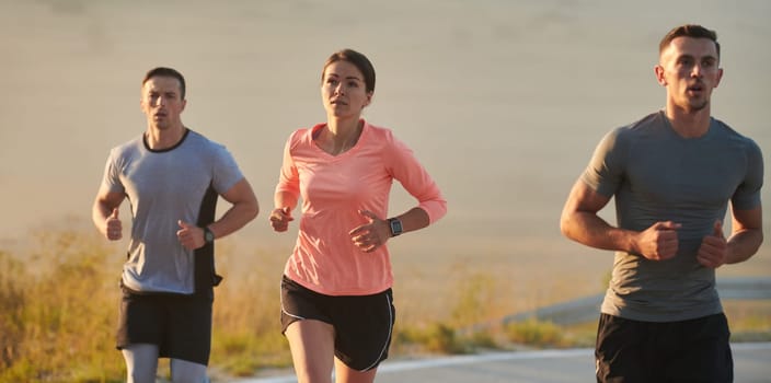 A group of friends, athletes, and joggers embrace the early morning hours as they run through the misty dawn, energized by the rising sun and surrounded by the tranquil beauty of nature.