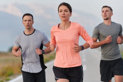 A group of friends, athletes, and joggers embrace the early morning hours as they run through the misty dawn, energized by the rising sun and surrounded by the tranquil beauty of nature.