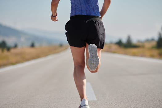 An athletic woman finds freedom and joy in a healthy lifestyle, running through a beautiful road trail at sunrise.