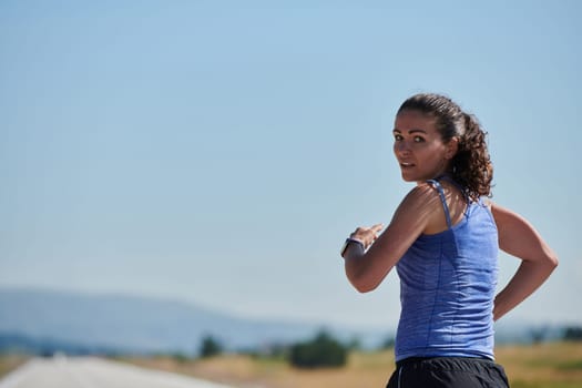 An athletic woman finds freedom and joy in a healthy lifestyle, running through a beautiful road trail at sunrise.