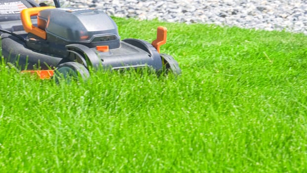 Castle Rock, Colorado, USA-June 25, 2023- At a residential suburban house, a lush green lawn is meticulously mowed using an electric lawn mower, creating a well-manicured and inviting outdoor space.