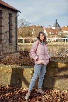 Young beautiful pretty tourist girl in warm hat and coat with backpack walking at cold autumn in Europe city enjoying her travel in Zurich Switzerland. Outdoor portrait of young tourist woman enjoying sightseeing