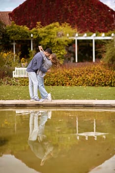 lovely young couple kissing outdoors in autumn. Loving couple walking in nature. Autumn mood. Happy man and woman hugging and kissing in autumn. Love. Fashionable couple outdoors. Fashion, people and lifestyle. Stylish couple in autumn outfit.