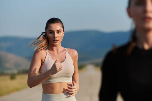 An athletic woman finds freedom and joy in a healthy lifestyle, running through a beautiful road trail at sunrise.