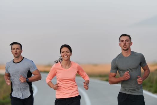 A group of friends, athletes, and joggers embrace the early morning hours as they run through the misty dawn, energized by the rising sun and surrounded by the tranquil beauty of nature.