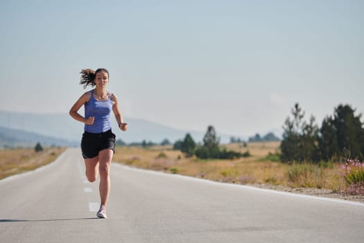 An athletic woman finds freedom and joy in a healthy lifestyle, running through a beautiful road trail at sunrise.