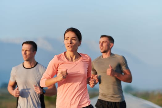 A group of friends, athletes, and joggers embrace the early morning hours as they run through the misty dawn, energized by the rising sun and surrounded by the tranquil beauty of nature.