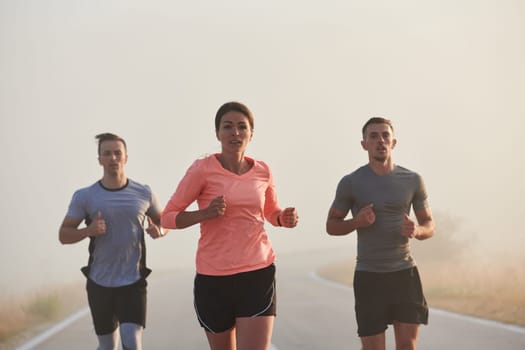 A group of friends, athletes, and joggers embrace the early morning hours as they run through the misty dawn, energized by the rising sun and surrounded by the tranquil beauty of nature.