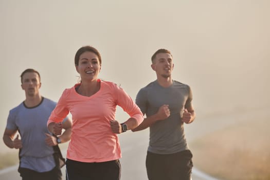 A group of friends, athletes, and joggers embrace the early morning hours as they run through the misty dawn, energized by the rising sun and surrounded by the tranquil beauty of nature.