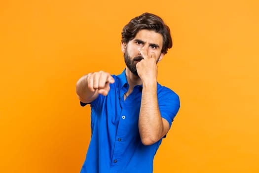 I am watching you. Young confident man pointing at her eyes and camera, show I am watching you gesture, spying on someone. Handsome attractive middle eastern guy isolated on orange studio background