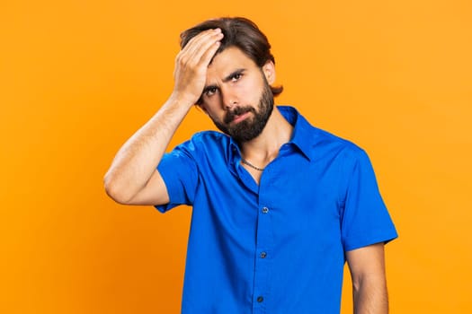 Face palm. Shame on you. Upset middle eastern young man making face palm gesture, feeling bored, disappointed in result, bad news, sorrowful. Unhappy guy isolated on orange studio background indoors
