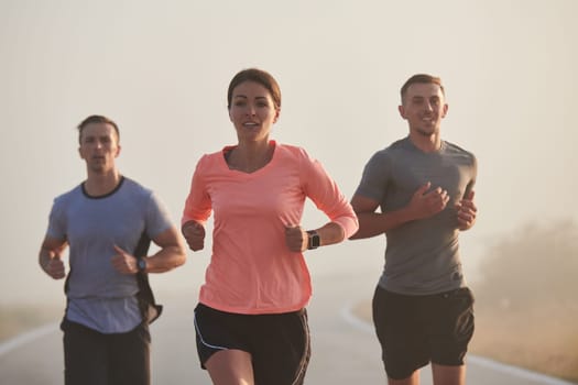 A group of friends, athletes, and joggers embrace the early morning hours as they run through the misty dawn, energized by the rising sun and surrounded by the tranquil beauty of nature.