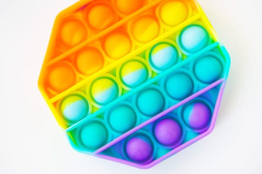 A colorful pop it fidget toy against a white background. The hexagonal toy has vibrant rainbow colors and bubbles to pop