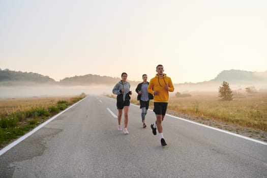 A group of friends, athletes, and joggers embrace the early morning hours as they run through the misty dawn, energized by the rising sun and surrounded by the tranquil beauty of nature.