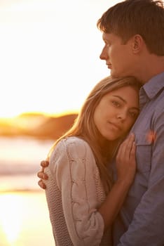 Couple, portrait and hug by beach at sunset, ocean waves and peace for romance in relationship. People, commitment and security in marriage, embrace and travel on vacation or holiday by mockup space.