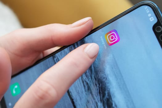 Close-up of a hand holding a smartphone with the Instagram app icon displayed