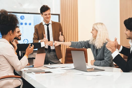 Corporate diverse businesspeople fist bump together while happy manager giving thumbs up at business meeting room. Represented unity, cooperation, dealing, making agreement, collaborate. Ornamented.