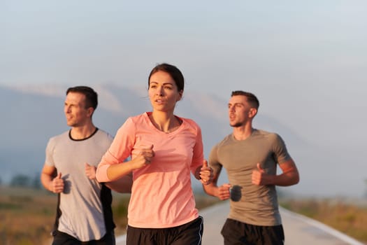 A group of friends, athletes, and joggers embrace the early morning hours as they run through the misty dawn, energized by the rising sun and surrounded by the tranquil beauty of nature.