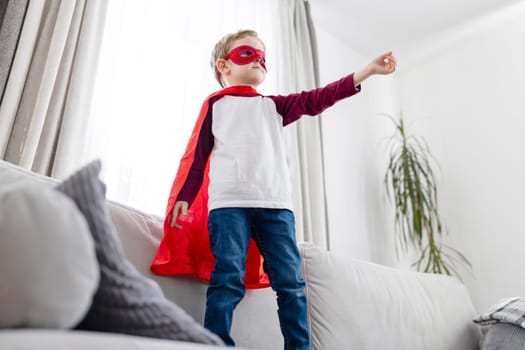 Young boy in superhero costume playing at home. Imagination and childhood concept. Design for children's books, educational content, playful advertising