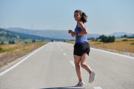 An athletic woman finds freedom and joy in a healthy lifestyle, running through a beautiful road trail at sunrise.