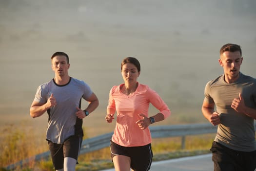 A group of friends, athletes, and joggers embrace the early morning hours as they run through the misty dawn, energized by the rising sun and surrounded by the tranquil beauty of nature.