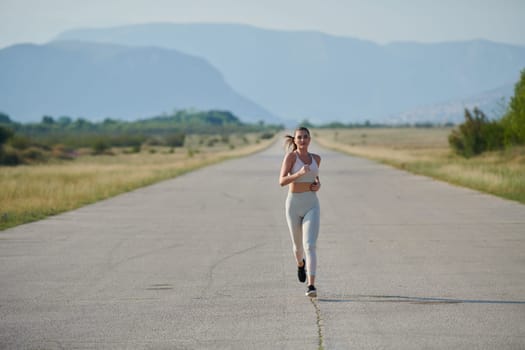 An athletic woman finds freedom and joy in a healthy lifestyle, running through a beautiful road trail at sunrise.