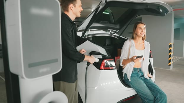 Electric car driver checks battery charging status, range and charging limit on app screen in the car. Smart technology device show EV car recharging data of electric storage in car battery innards.