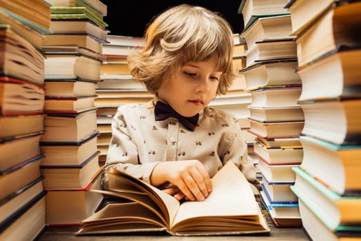 Handsome little child flips through the book pages in library. Elementary school boy enjoying reading in bookshop or bookstore. High quality