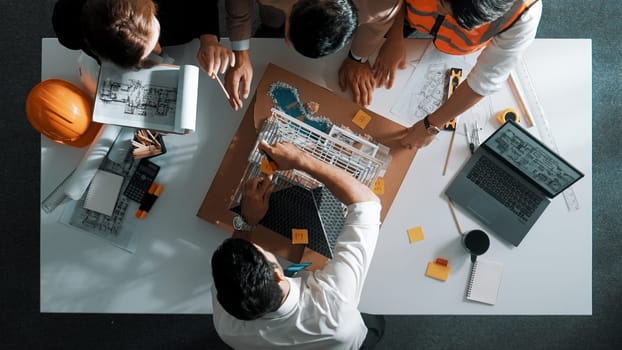 Top view of manager handed blueprint to professional engineer team at meeting table with house model and project plan. Group of architect discussing about design while receive document. Alimentation.