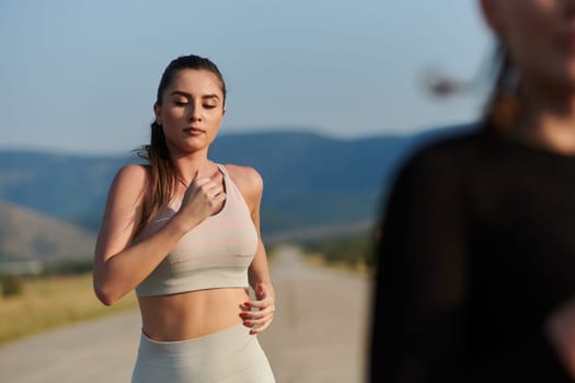 An athletic woman finds freedom and joy in a healthy lifestyle, running through a beautiful road trail at sunrise.