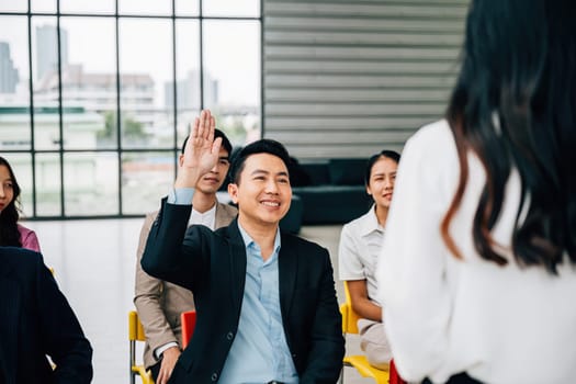 Within a conference, a young man raises his hand with eagerness to ask a question. The group is a prime example of collaborative teamwork and enthusiastic discussion, endorsing active learning.