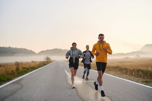 A group of friends, athletes, and joggers embrace the early morning hours as they run through the misty dawn, energized by the rising sun and surrounded by the tranquil beauty of nature.