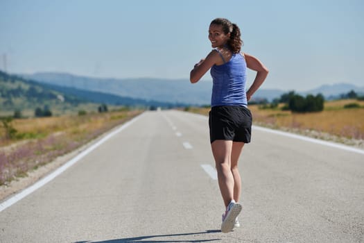 An athletic woman finds freedom and joy in a healthy lifestyle, running through a beautiful road trail at sunrise.