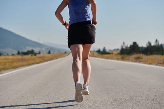 An athletic woman finds freedom and joy in a healthy lifestyle, running through a beautiful road trail at sunrise.