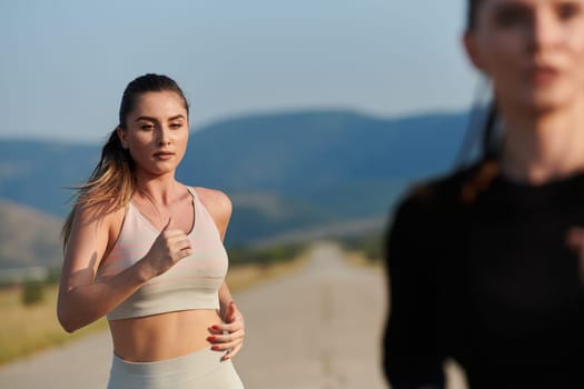 An athletic woman finds freedom and joy in a healthy lifestyle, running through a beautiful road trail at sunrise.