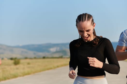 An athletic woman finds freedom and joy in a healthy lifestyle, running through a beautiful road trail at sunrise.